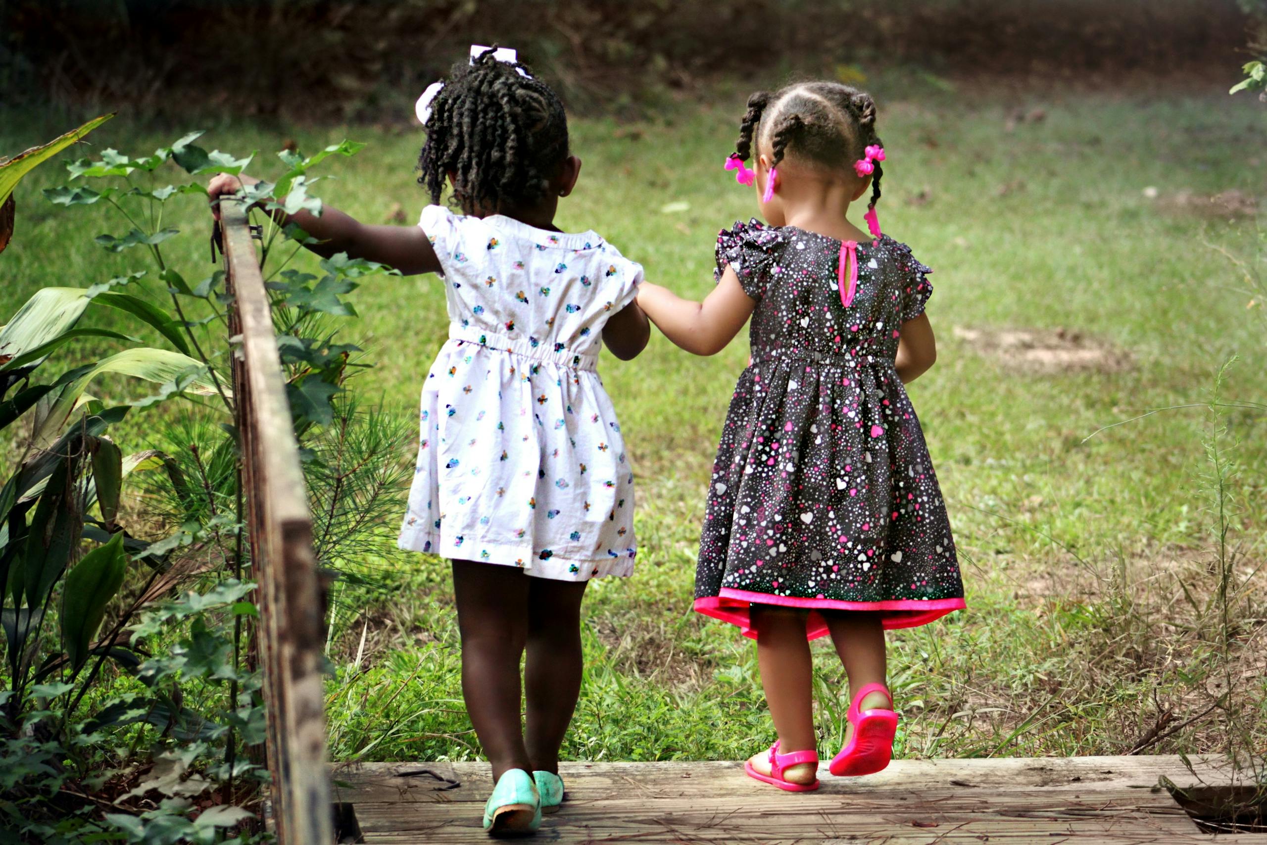 2 Girl Walking on Brown Bridge during Daytime